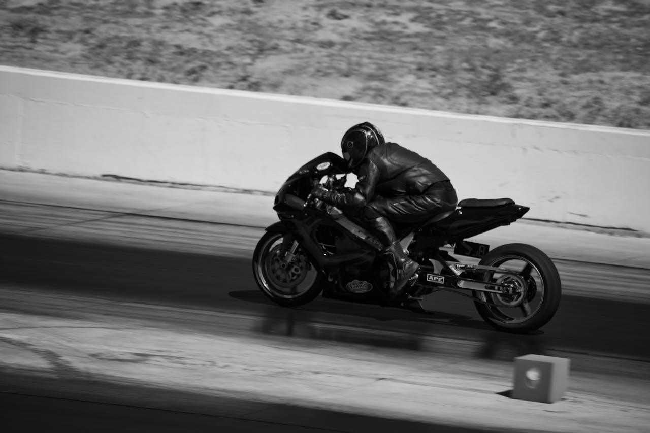 Black and white photograph capturing a motorcyclist in action during a high-speed race.